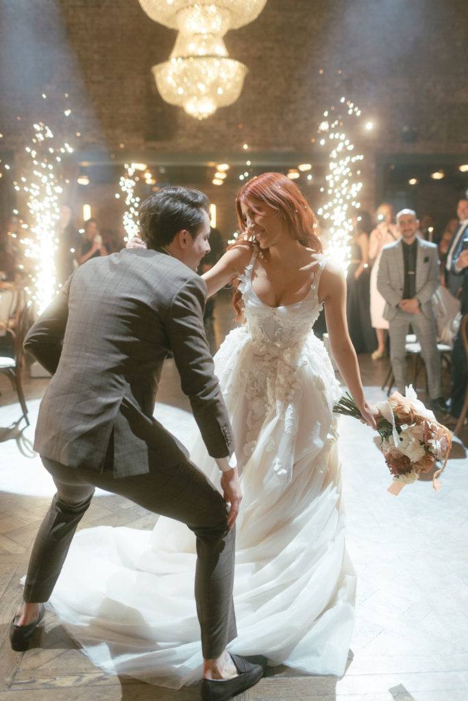 Couple enters their wedding reception with fireworks in background, and they're dancing